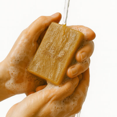 Mains savonneuses tenant un savon sous l'eau.