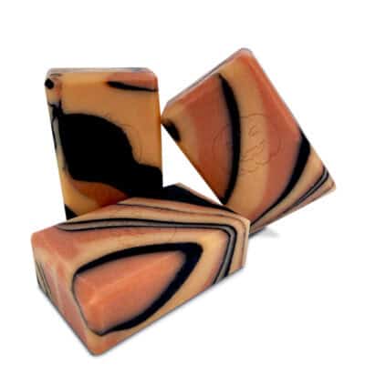 Trois savons artisanaux marbrés orange et noir.