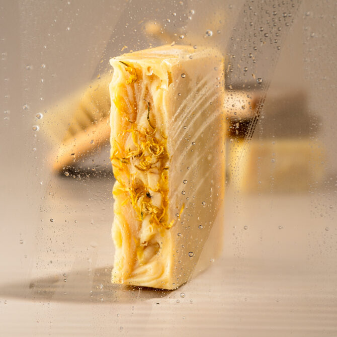 Savon artisanal avec fleurs séchées derrière verre embué.